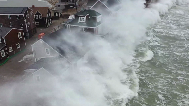 Massive waves crash over top of coastal homes