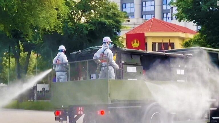 Soldiers in hazmat suits spray disinfectant down streets in Vietnam