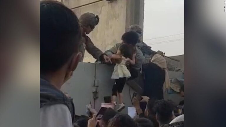 Afghan man hands child over barbed wire to soldier at Kabul airport